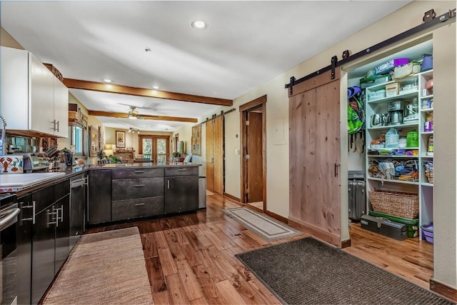 kitchen featuring a barn door, a peninsula, dark wood-type flooring, a sink, and white cabinets