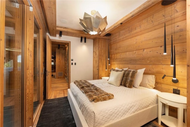 bedroom with hardwood / wood-style floors, wood walls, and beam ceiling