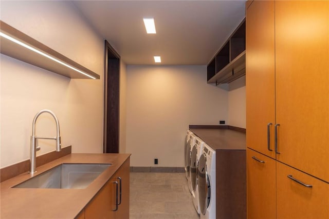 clothes washing area featuring cabinets, washing machine and dryer, and sink