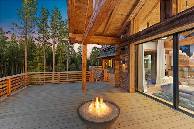 deck at dusk featuring a fire pit