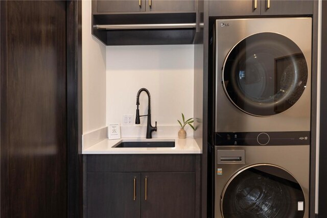 laundry room featuring stacked washer / dryer, sink, and cabinets