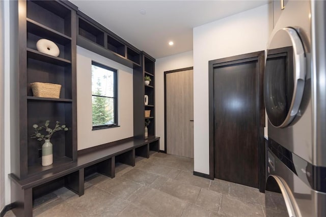 mudroom with built in shelves and stacked washing maching and dryer