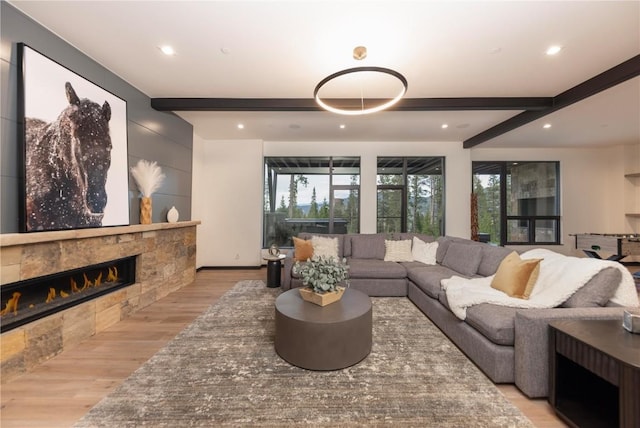 living room featuring beamed ceiling, light hardwood / wood-style floors, and a tile fireplace