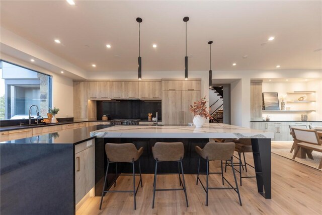 kitchen with pendant lighting, light wood-type flooring, a kitchen breakfast bar, and light brown cabinetry