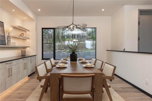 dining room with a wealth of natural light, an inviting chandelier, and light wood-type flooring