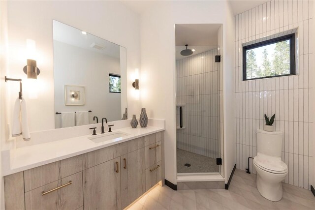 bathroom featuring tile patterned flooring, an enclosed shower, toilet, vanity, and tile walls