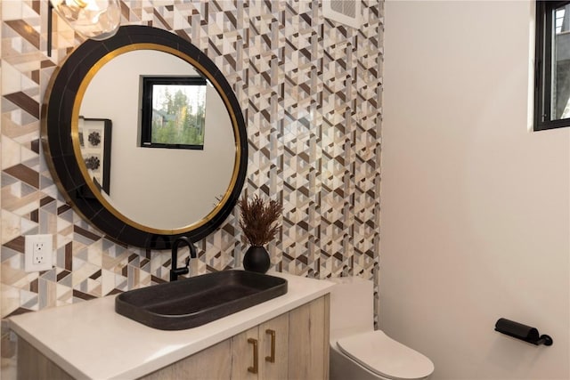 bathroom featuring tasteful backsplash, vanity, and toilet