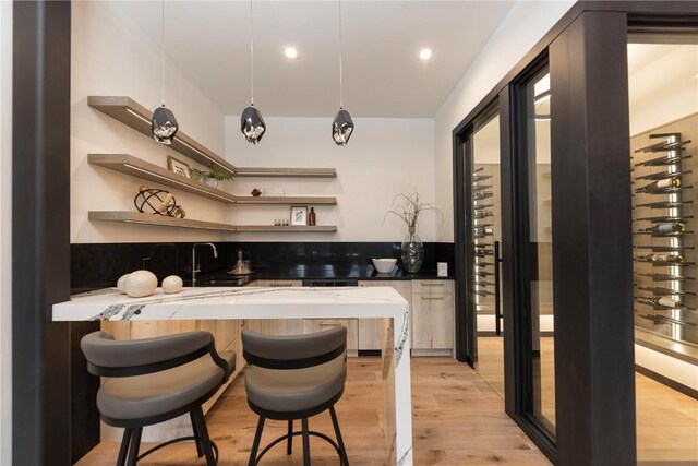 bar featuring pendant lighting, light hardwood / wood-style floors, and sink