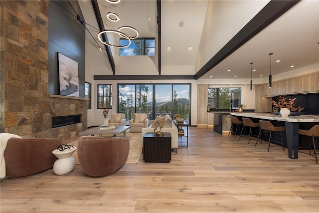 living room with a fireplace, high vaulted ceiling, and light wood-type flooring