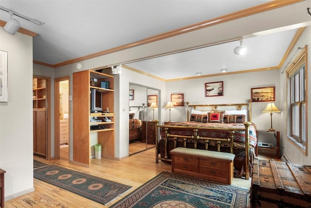 bedroom with track lighting, crown molding, ensuite bath, light wood-type flooring, and a closet