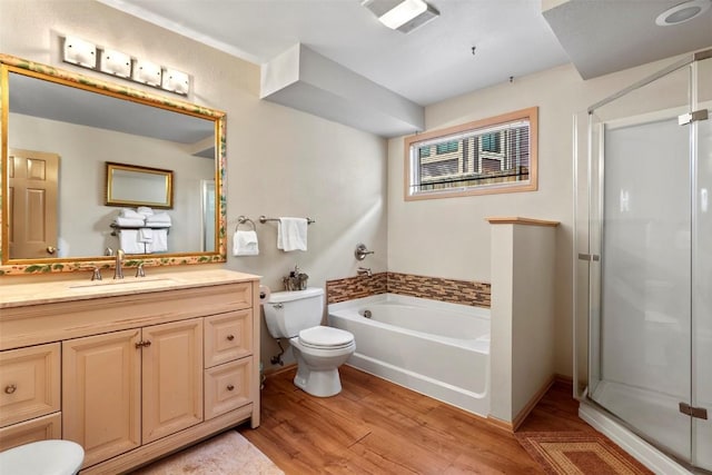 full bathroom with vanity, toilet, plus walk in shower, and hardwood / wood-style flooring