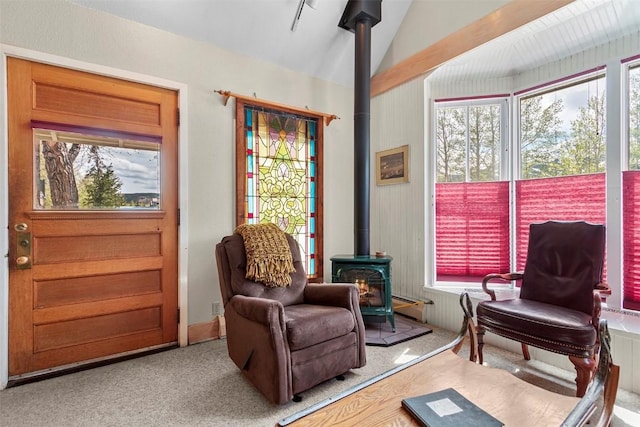 living area with a wood stove, a baseboard radiator, and lofted ceiling