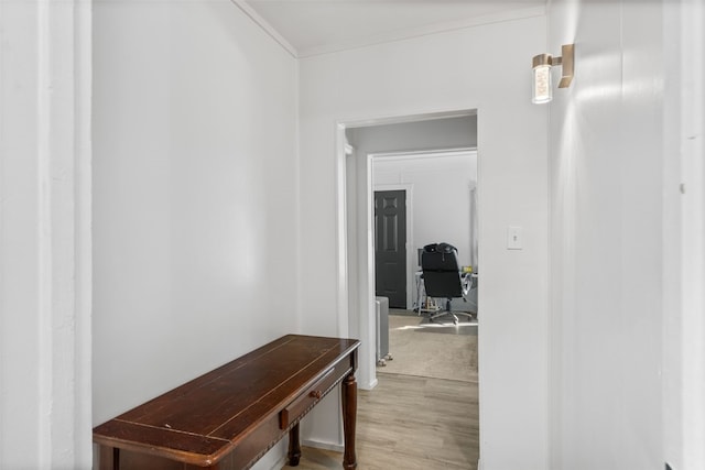 corridor featuring ornamental molding and light wood-style flooring