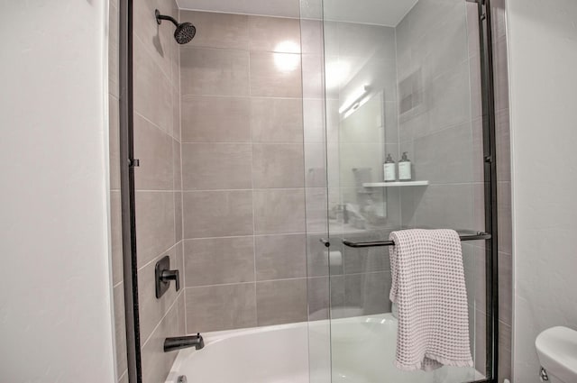 bathroom featuring toilet and bath / shower combo with glass door