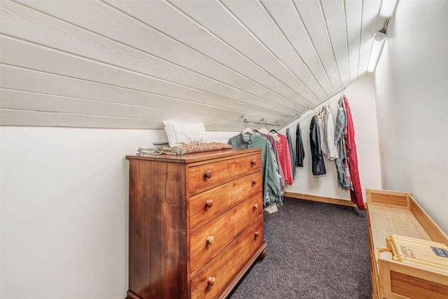 walk in closet with vaulted ceiling and dark colored carpet