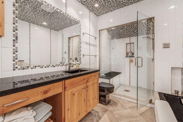 bathroom with tile walls, vanity, a shower with shower door, and toilet