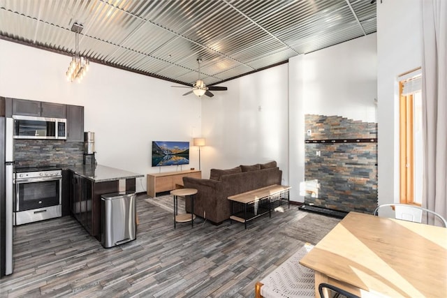 living room featuring ceiling fan, dark hardwood / wood-style flooring, and a high ceiling