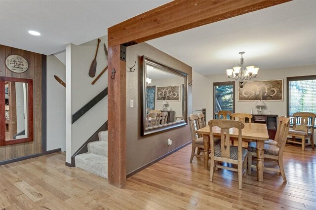 dining area with wooden walls, a chandelier, and light wood-type flooring