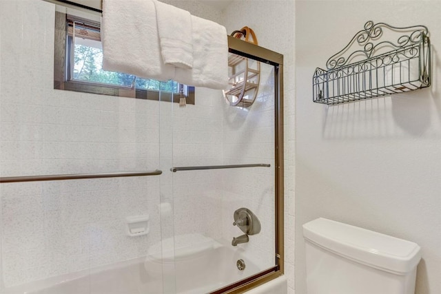 bathroom featuring bath / shower combo with glass door and toilet