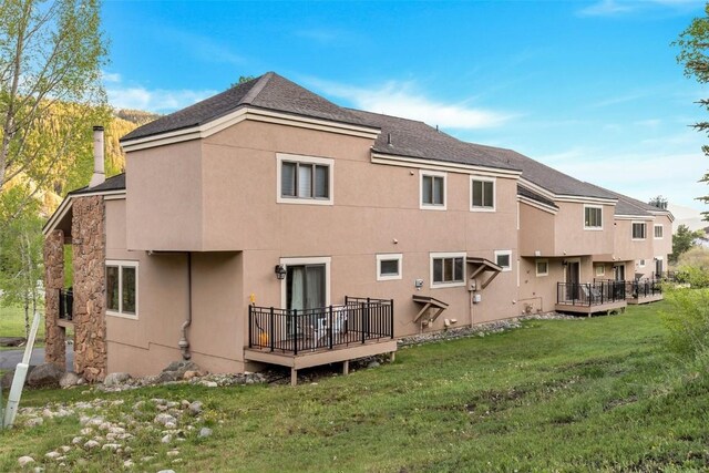 rear view of house with a lawn and a deck