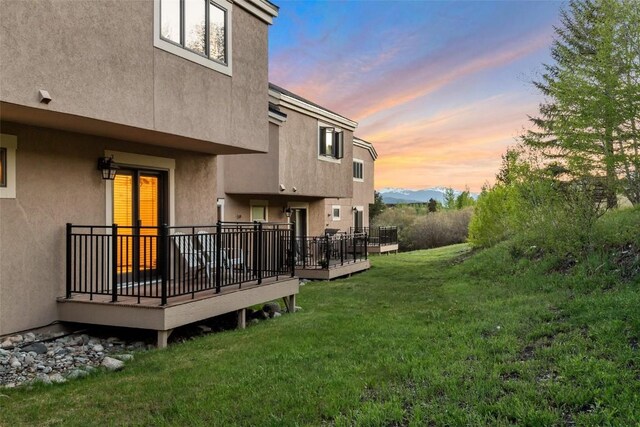 yard at dusk featuring a wooden deck