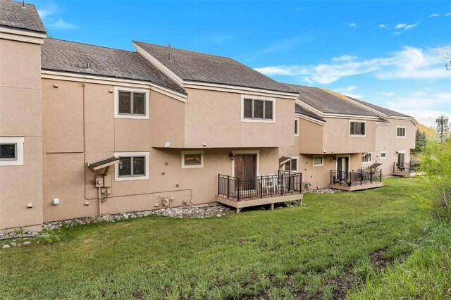 rear view of property with a wooden deck and a yard