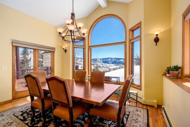 dining area featuring vaulted ceiling with beams, an inviting chandelier, light hardwood / wood-style flooring, a baseboard radiator, and a mountain view