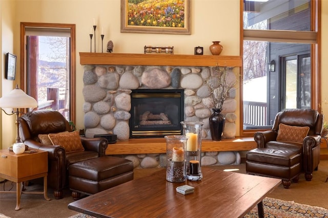 living room with a stone fireplace and carpet floors