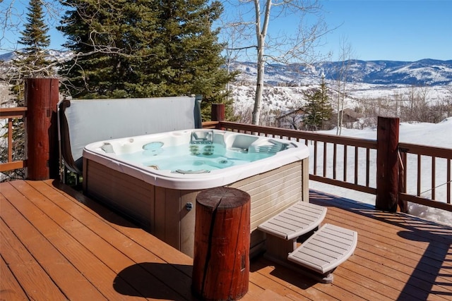 snow covered deck with a mountain view and a hot tub