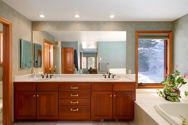 bathroom featuring vanity, tiled bath, and toilet