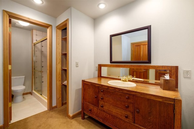 bathroom featuring vanity, toilet, and a shower with door