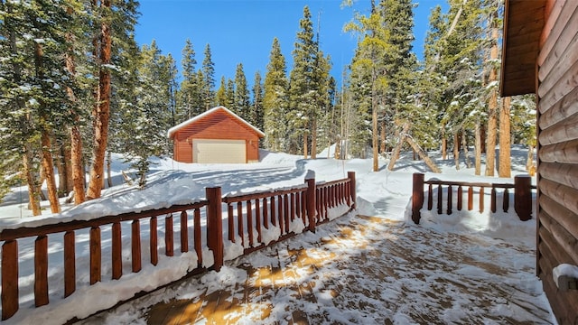 snowy yard with a garage and an outbuilding