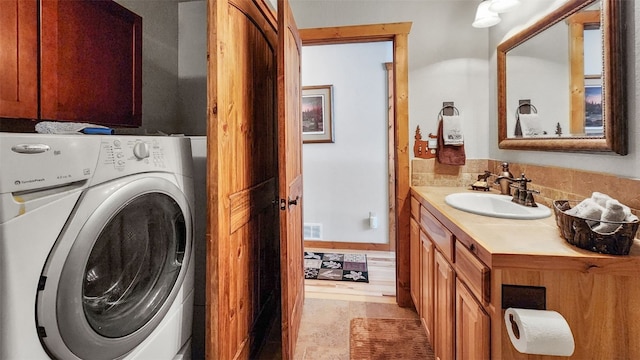 laundry area with visible vents, cabinet space, a sink, and washer / dryer