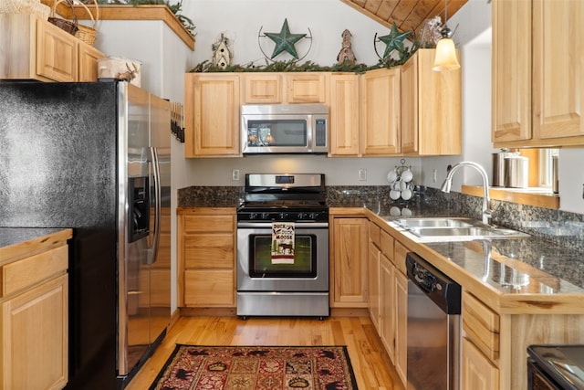 kitchen featuring lofted ceiling, light brown cabinets, light wood-style flooring, a sink, and appliances with stainless steel finishes