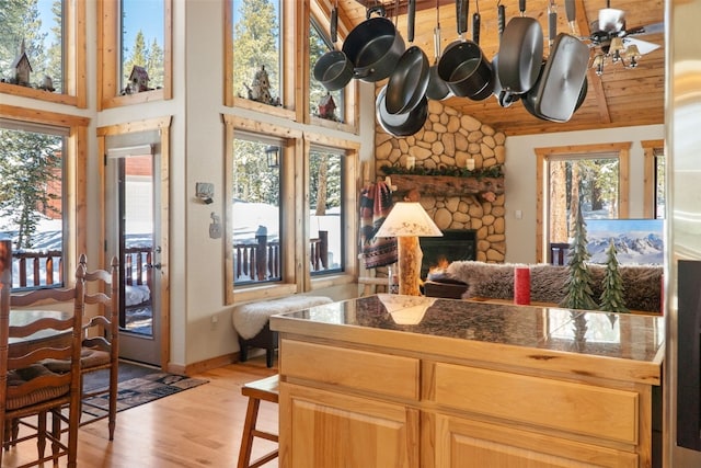 kitchen with tile countertops, high vaulted ceiling, a stone fireplace, wood ceiling, and light wood finished floors