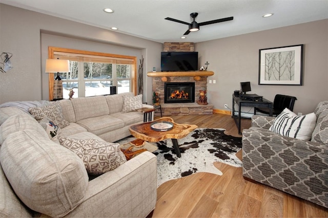 living area featuring recessed lighting, a ceiling fan, wood finished floors, and a stone fireplace