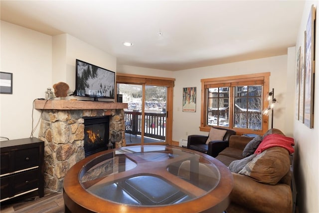 living room with hardwood / wood-style floors, a stone fireplace, and baseboard heating