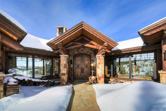 snow covered property entrance featuring stone siding