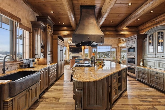 kitchen featuring beam ceiling, island exhaust hood, wood ceiling, and a sink