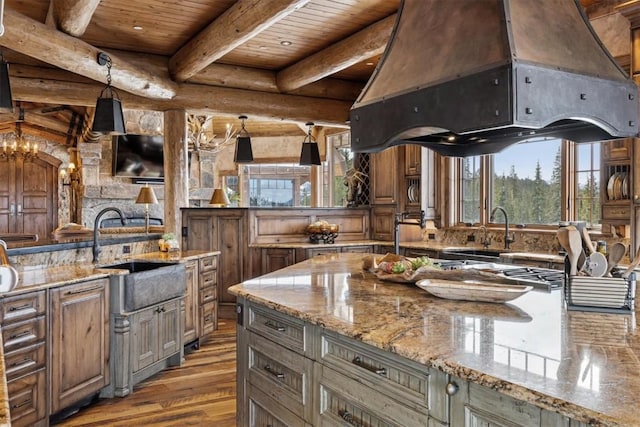 kitchen featuring beamed ceiling, wooden ceiling, wood finished floors, custom exhaust hood, and a sink