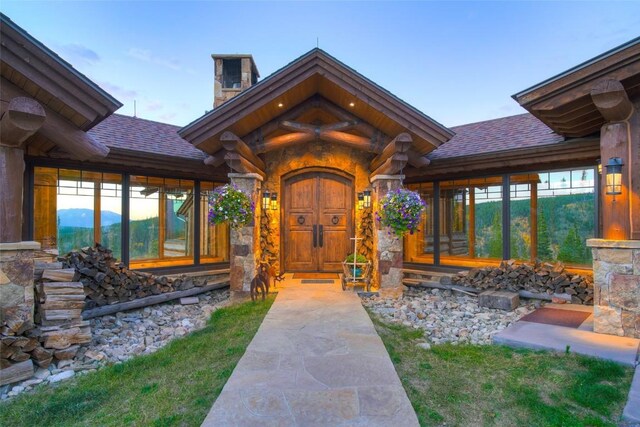 doorway to property featuring a chimney and a shingled roof