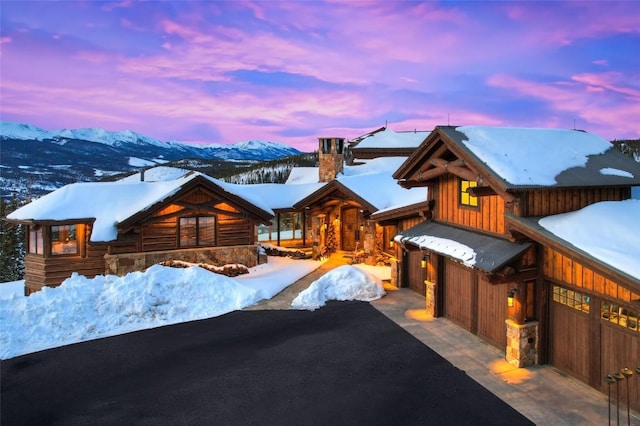 view of front of house with aphalt driveway, a mountain view, board and batten siding, and a chimney