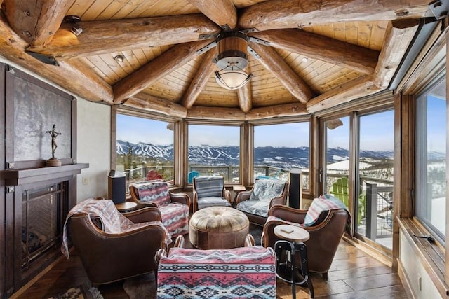 sunroom / solarium featuring beam ceiling, a fireplace, a mountain view, and wooden ceiling