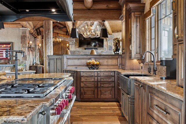 kitchen with light stone countertops, custom range hood, sink, and wood ceiling