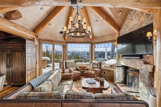 living area with wood finished floors, high vaulted ceiling, beam ceiling, an inviting chandelier, and a stone fireplace