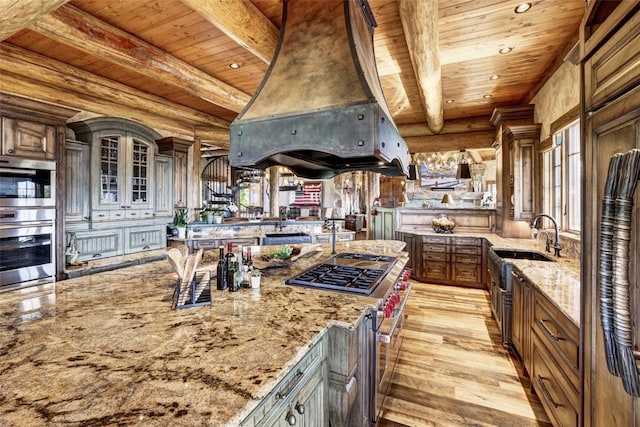 kitchen featuring appliances with stainless steel finishes, light stone counters, log walls, custom exhaust hood, and wooden ceiling