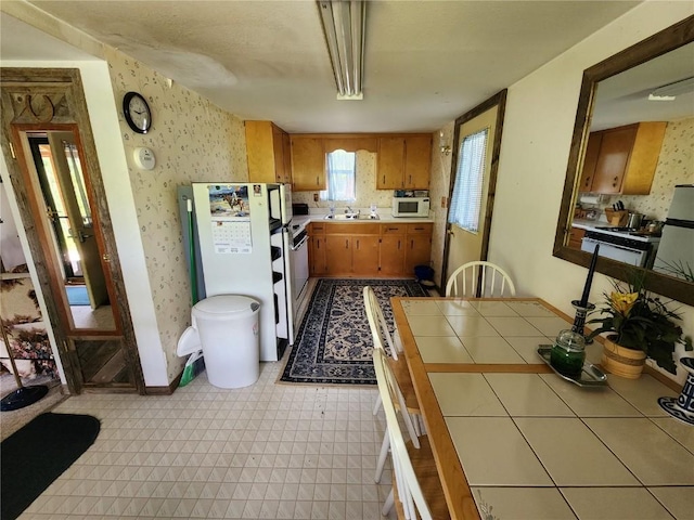 kitchen featuring pendant lighting, white appliances, tile countertops, and sink