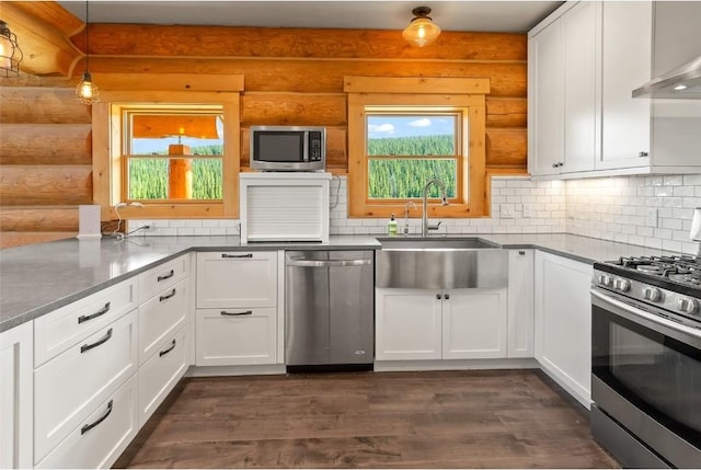 kitchen with pendant lighting, white cabinets, sink, dark hardwood / wood-style floors, and appliances with stainless steel finishes