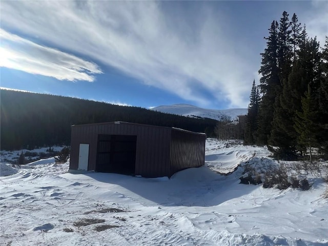 snow covered structure with a mountain view and a garage