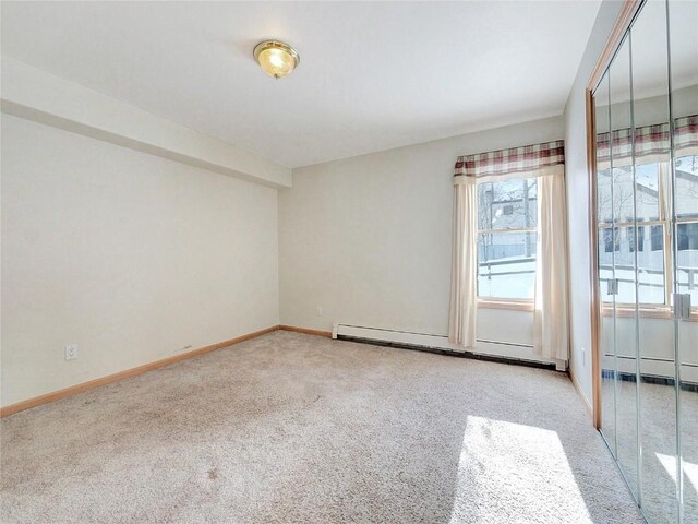 spare room featuring light carpet and a baseboard heating unit